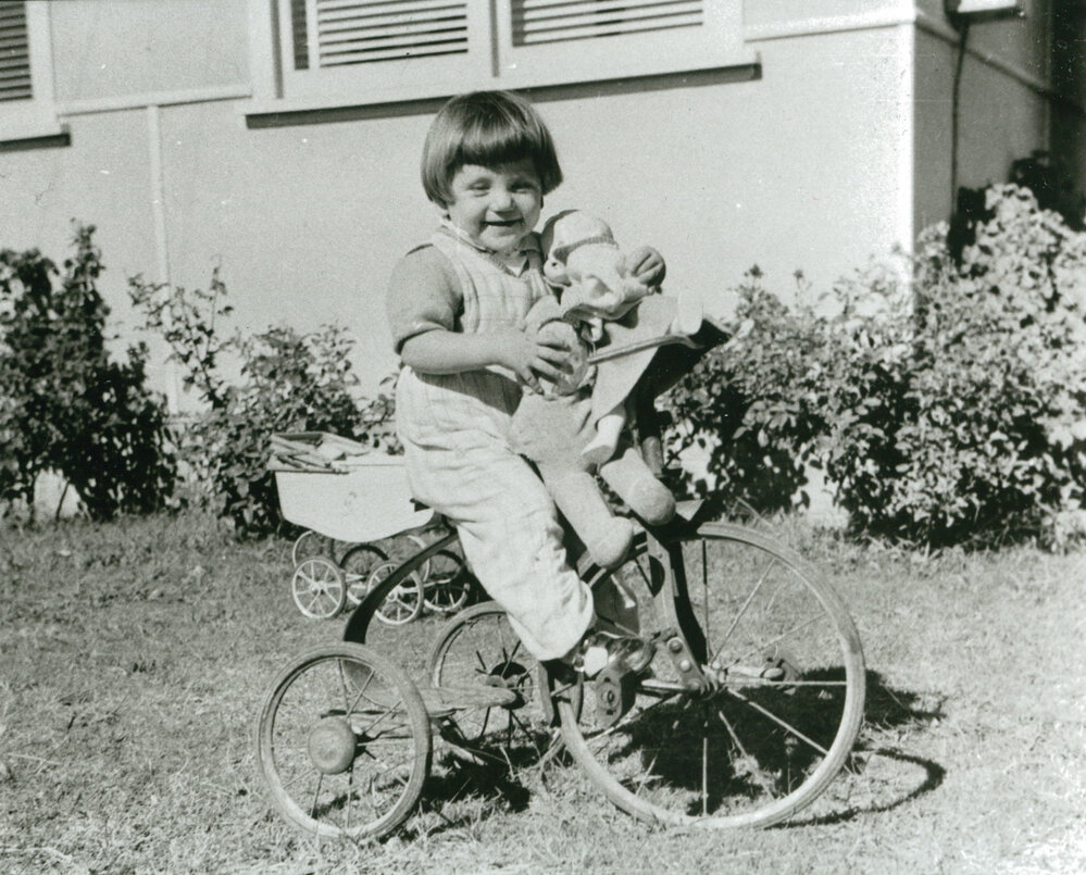 Judy Kirchmajer on her tricycle with her doll 'Morny'